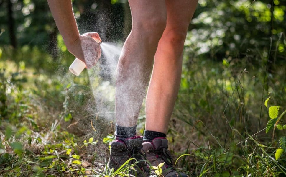 Homemade Mosquito Repellent being sprayed onto the skin of legs out on grass